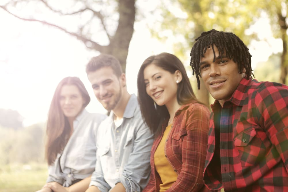 A diverse group of friends sitting outdoors together, smiling